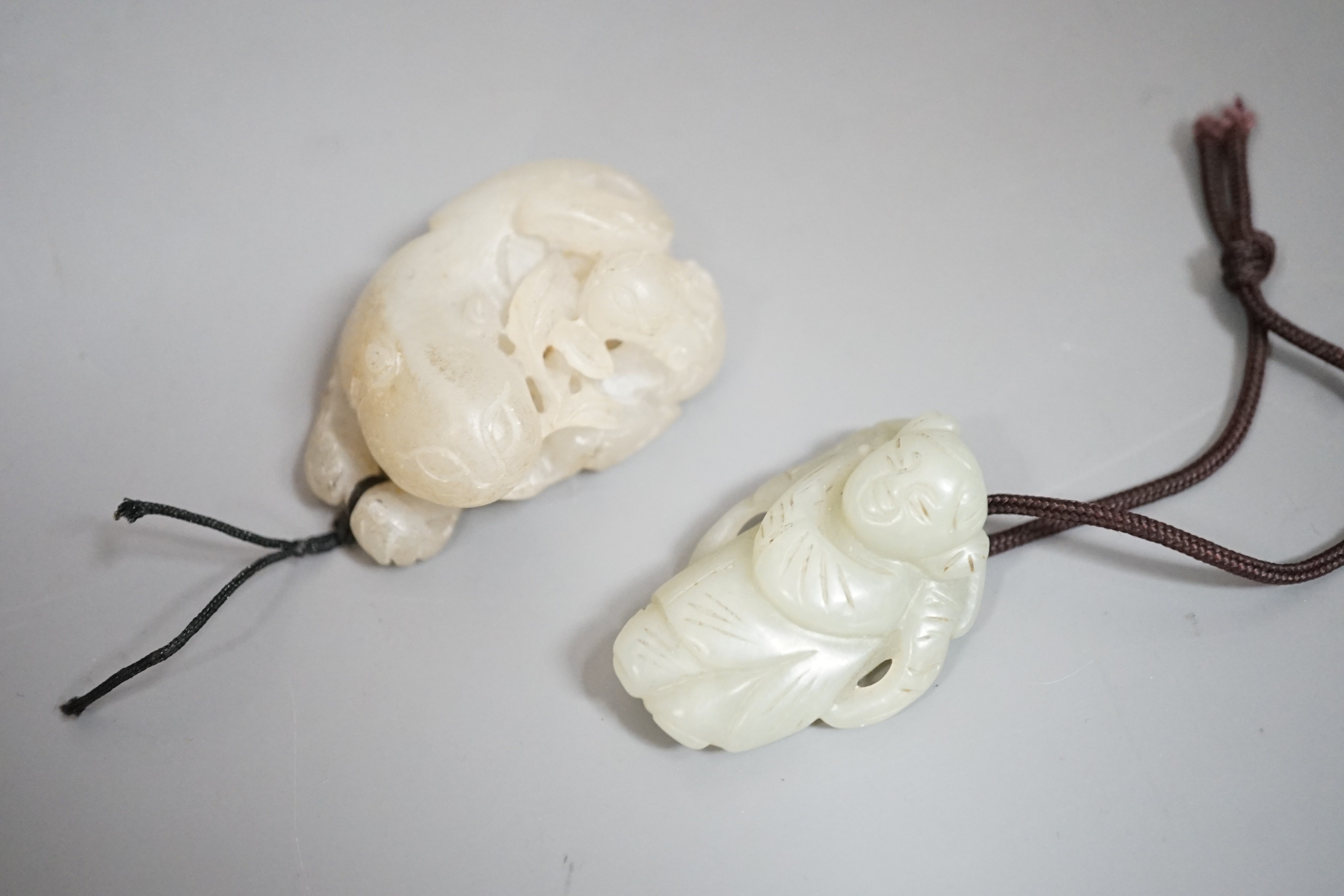 A Chinese pale celadon jade lion dog and cub and a similar figure of a boy, 19th/20th century